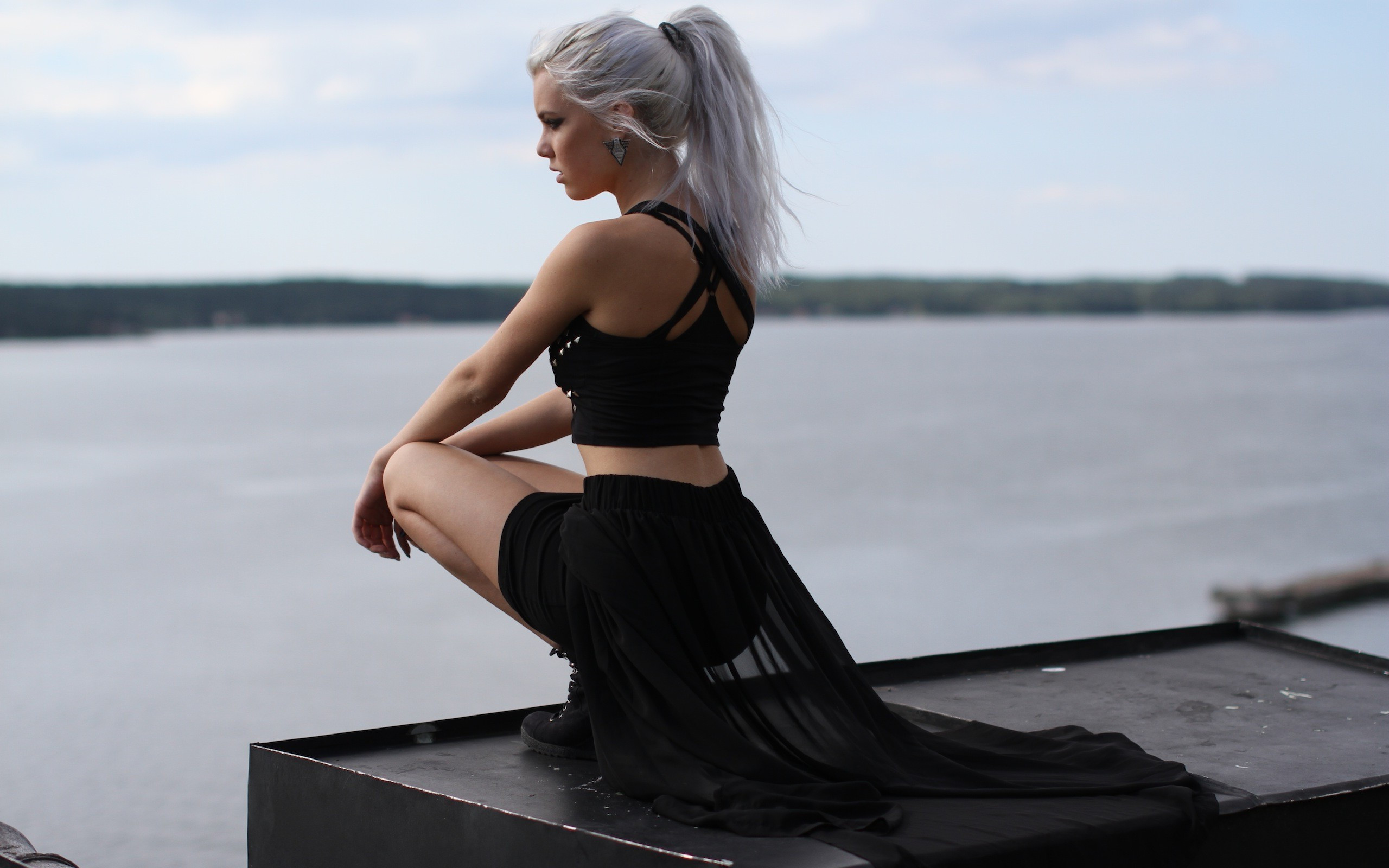 Free photo A blonde-haired girl in a beautiful suit sits on a pier