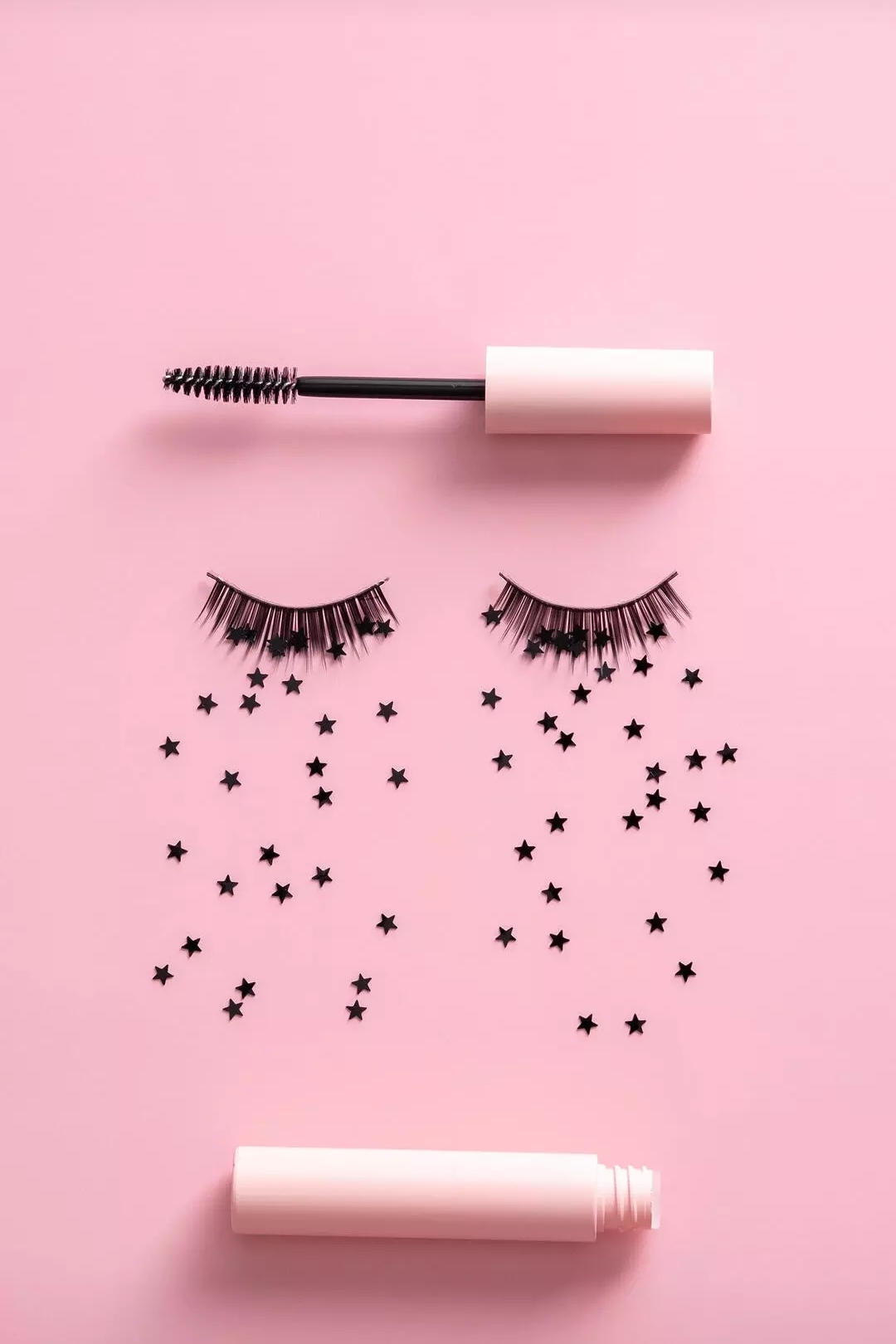 Free photo Creative flat composition with mascara, false eyelashes and confetti on a pink background