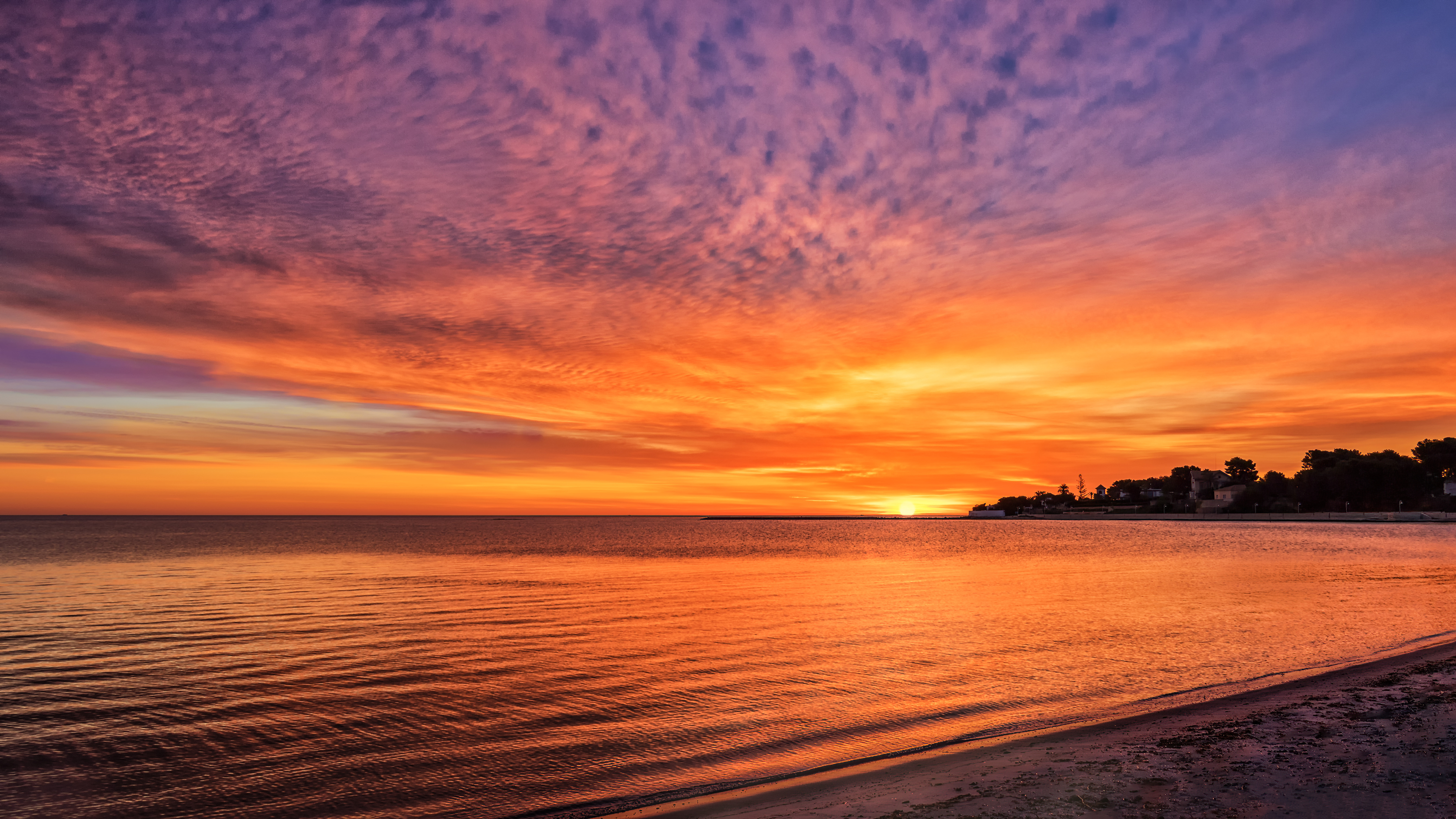 Free photo Amber sky with clouds during sunset on the beach front