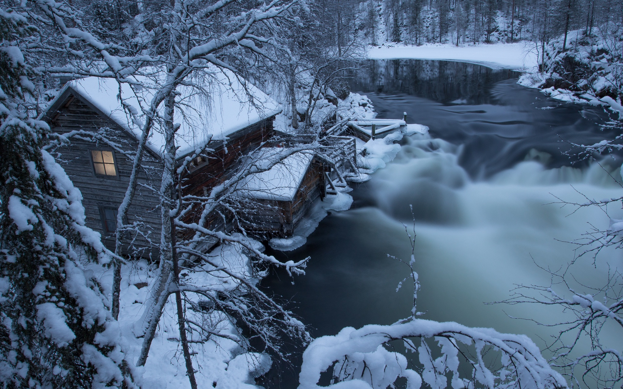 Free photo A house on the bank of a river with a strong current on a frosty winter day