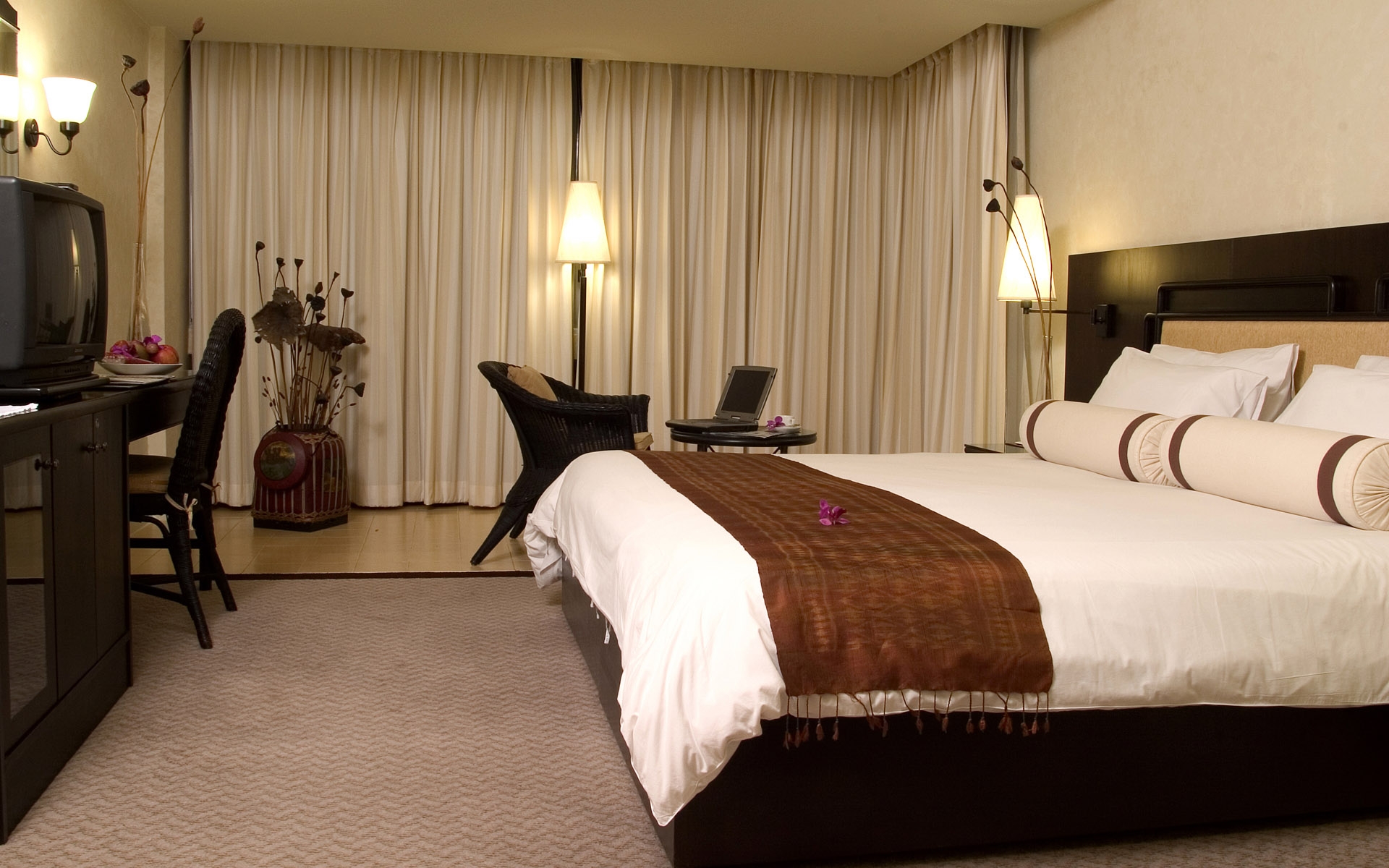 Бесплатное фото Номер в отеле с большой кроватью, креслом, телевизором и рабочим столом.