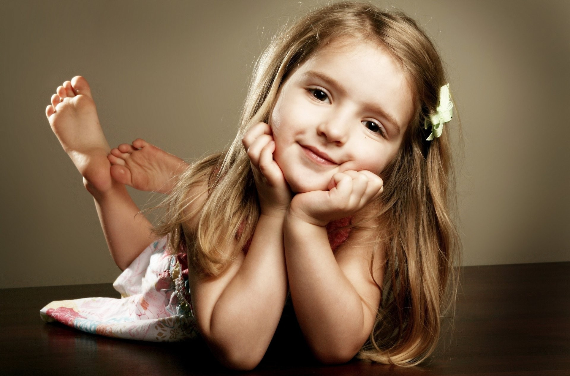 Free photo A little girl lying on her stomach and looking at the camera